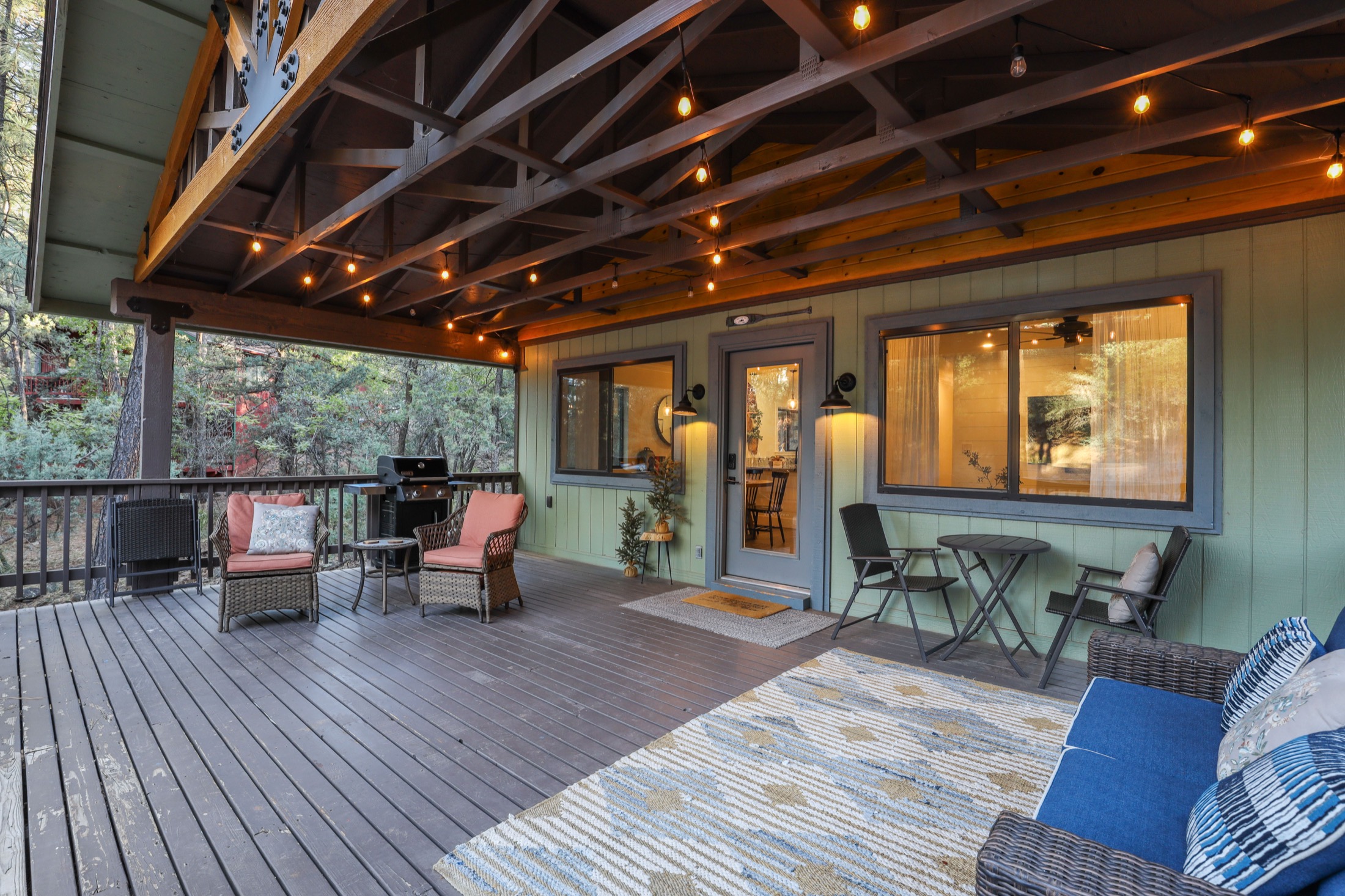 Covered deck with string lights and lounge seating at Serenity Pines Hideaway